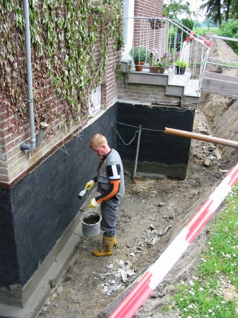 Fachkraft die nachträglich eine erdberührten Kelleraußenwand abdichtet